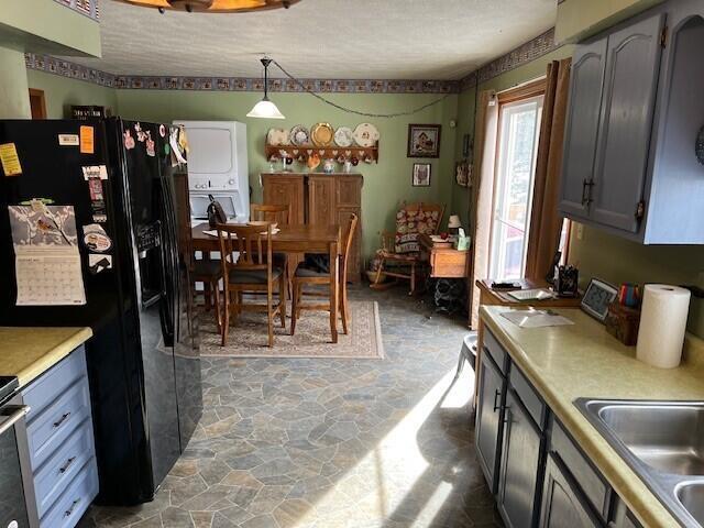 kitchen with black fridge, gray cabinets, sink, and hanging light fixtures