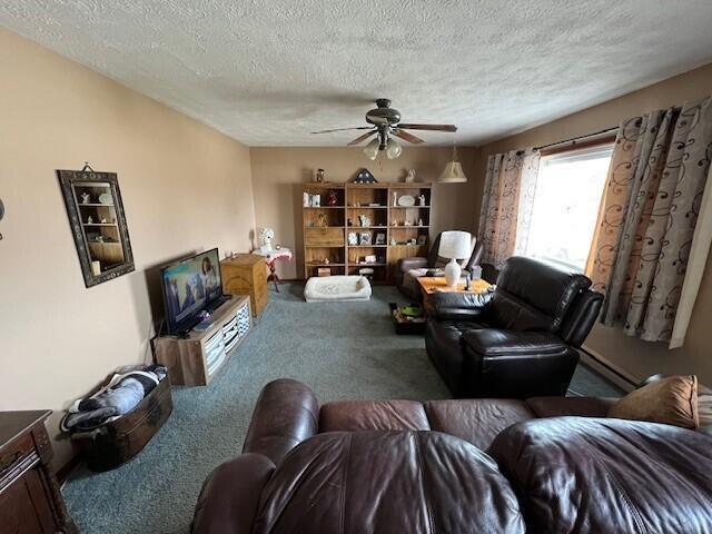 living room with ceiling fan, carpet floors, and a textured ceiling