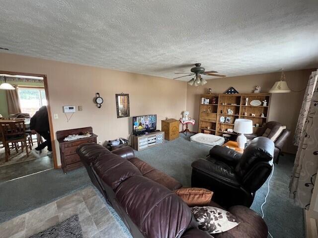 living room with ceiling fan and a textured ceiling