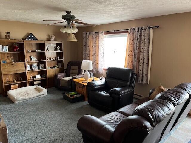 sitting room with a baseboard heating unit, ceiling fan, a textured ceiling, and carpet flooring