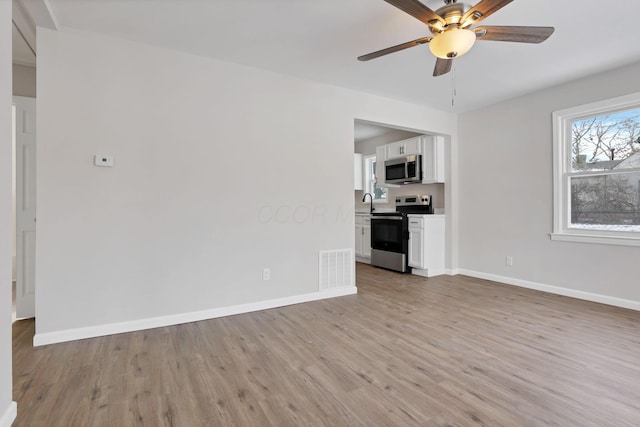 unfurnished living room featuring ceiling fan, sink, and light hardwood / wood-style floors