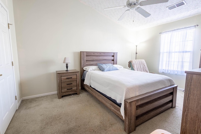 bedroom featuring light carpet, ceiling fan, vaulted ceiling, and a textured ceiling