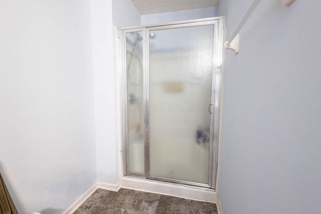 bathroom featuring a shower with door and a textured ceiling