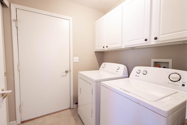 laundry room featuring washer and dryer, cabinets, and a textured ceiling