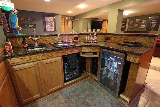 bar featuring wine cooler, sink, and dark stone countertops