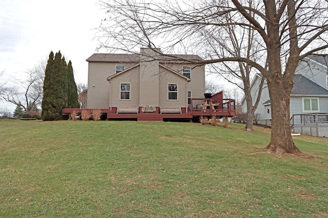 rear view of property with a wooden deck and a lawn