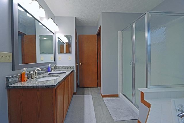 bathroom with a shower with door, wood-type flooring, vanity, and a textured ceiling