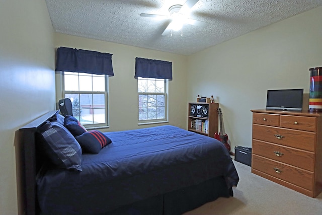 carpeted bedroom with ceiling fan and a textured ceiling