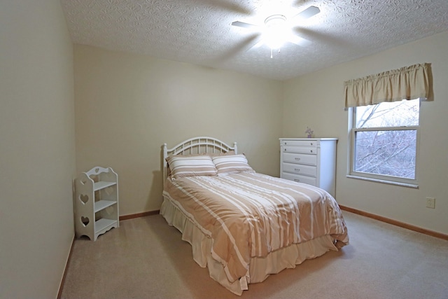 bedroom with ceiling fan, light colored carpet, and a textured ceiling