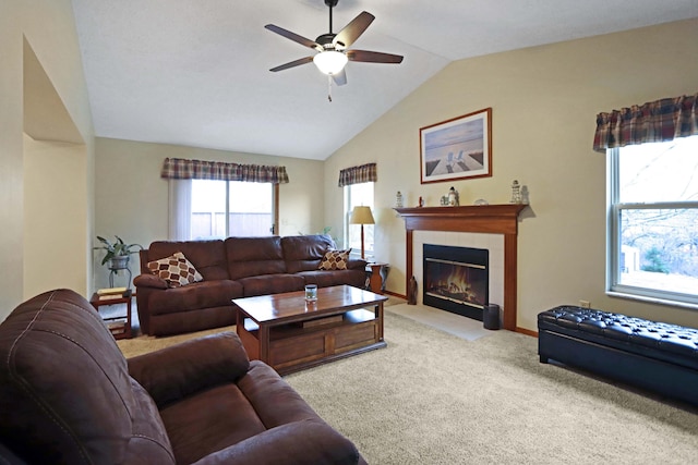 carpeted living room with ceiling fan, lofted ceiling, and a tile fireplace