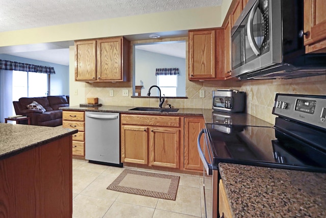 kitchen featuring sink, light tile patterned floors, a wealth of natural light, stainless steel appliances, and backsplash