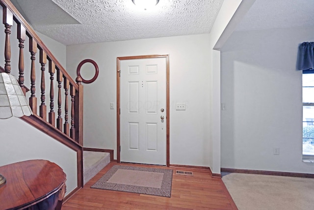 foyer entrance featuring light hardwood / wood-style floors and a textured ceiling