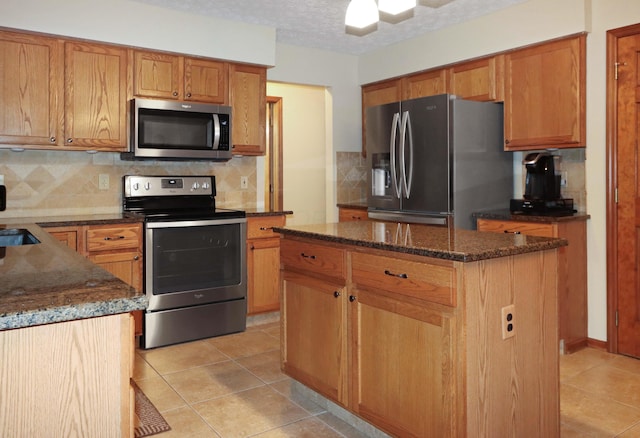 kitchen with dark stone countertops, backsplash, stainless steel appliances, a center island, and a textured ceiling