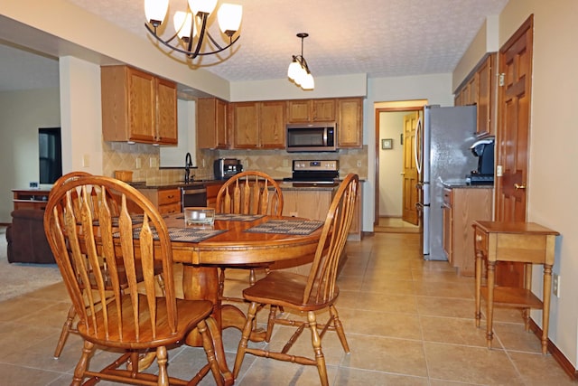 tiled dining area with a chandelier, sink, and a textured ceiling