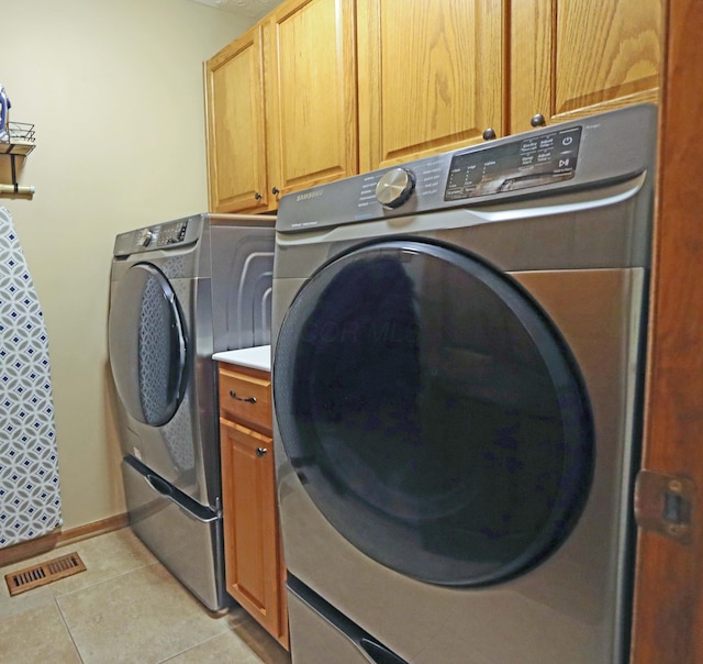 laundry area featuring cabinets, light tile patterned flooring, and separate washer and dryer