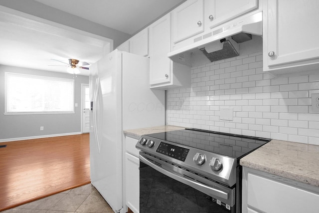 kitchen featuring light stone counters, light tile patterned floors, white cabinets, electric stove, and backsplash