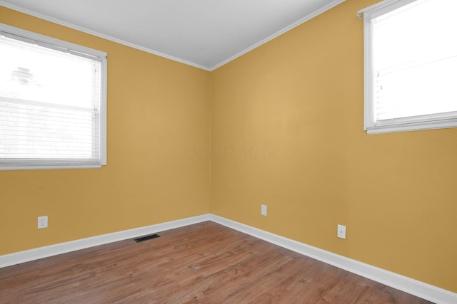 unfurnished room with ornamental molding, plenty of natural light, and hardwood / wood-style floors