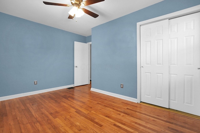 unfurnished bedroom with hardwood / wood-style flooring, ceiling fan, and a closet