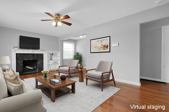 living room with wood-type flooring, ceiling fan, and a fireplace