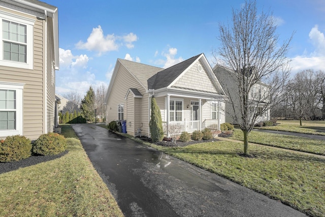 view of side of home featuring a yard and covered porch