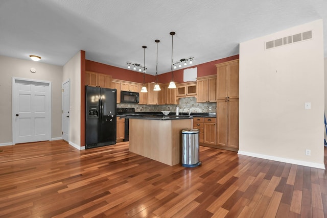 kitchen featuring hanging light fixtures, backsplash, black appliances, a kitchen island, and dark hardwood / wood-style flooring