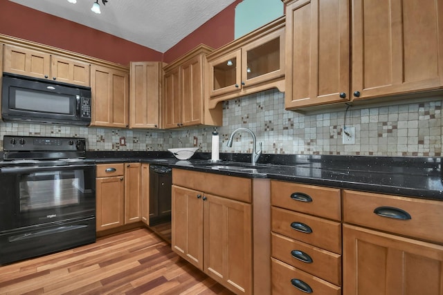 kitchen featuring dark stone countertops, decorative backsplash, light hardwood / wood-style flooring, and black appliances