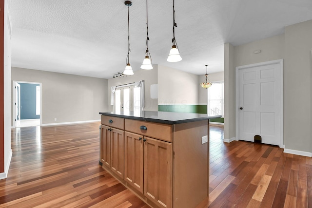 kitchen featuring dark hardwood / wood-style flooring, hanging light fixtures, a textured ceiling, and a kitchen island