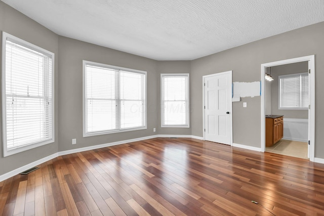 empty room featuring hardwood / wood-style flooring, plenty of natural light, and a textured ceiling