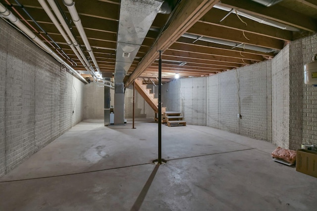 basement featuring brick wall and heating unit