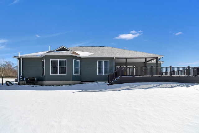 snow covered house featuring central AC and a deck