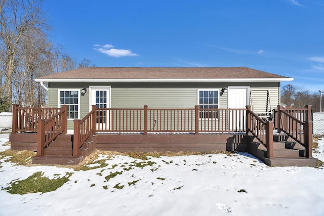 snow covered rear of property with a wooden deck