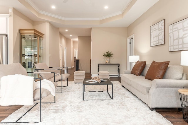 living room with crown molding, wood-type flooring, a raised ceiling, and ceiling fan