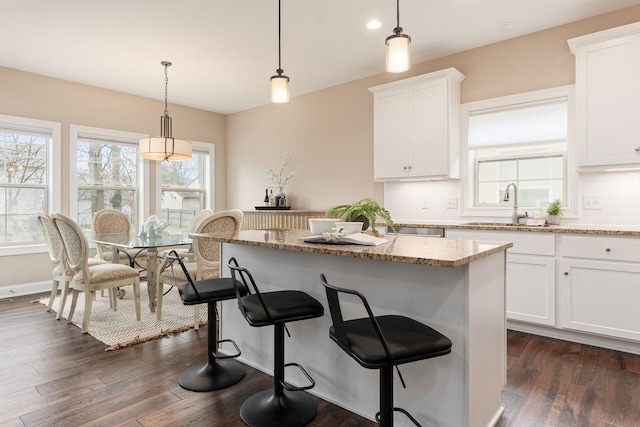 kitchen with white cabinetry, hanging light fixtures, and a kitchen island