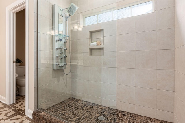 bathroom featuring tiled shower and toilet