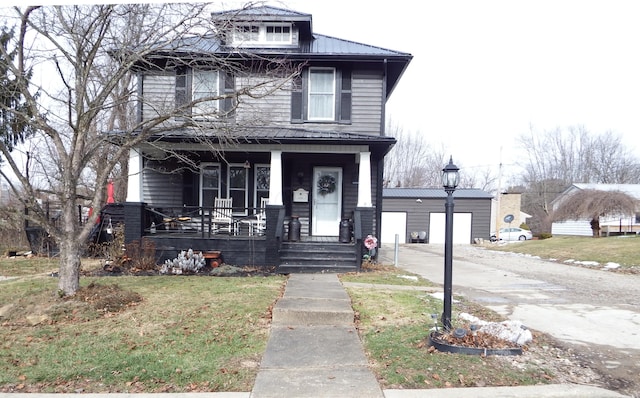 view of front of property featuring a garage, an outbuilding, a front yard, and covered porch