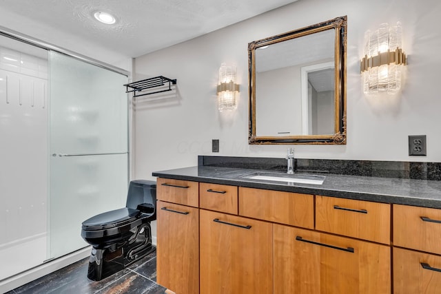 bathroom with a shower with door, vanity, a textured ceiling, and toilet