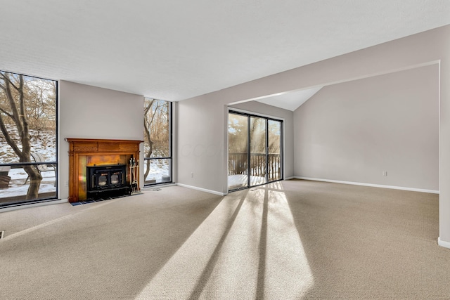 unfurnished living room with lofted ceiling, carpet floors, and a healthy amount of sunlight