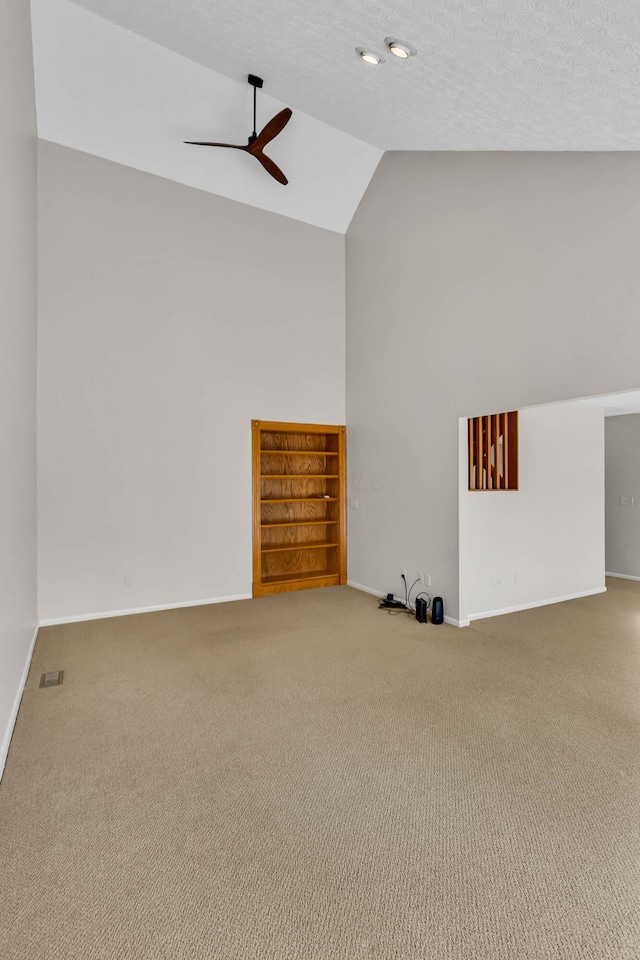 carpeted empty room with ceiling fan, vaulted ceiling, and a textured ceiling