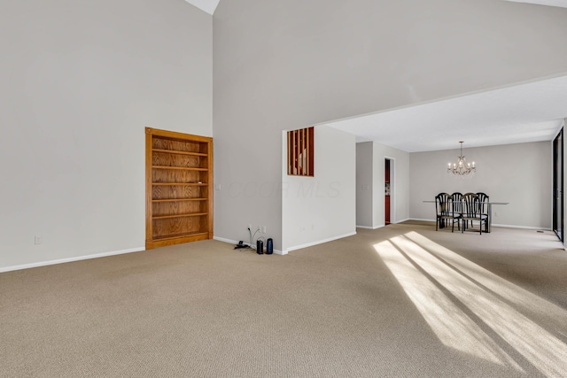 carpeted spare room with built in shelves, a towering ceiling, and a notable chandelier