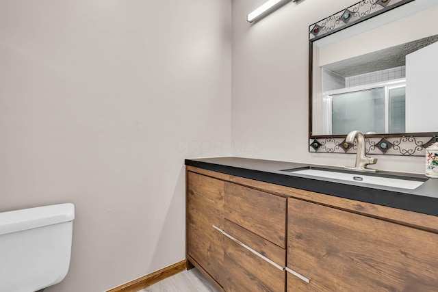 bathroom with vanity, an enclosed shower, and toilet