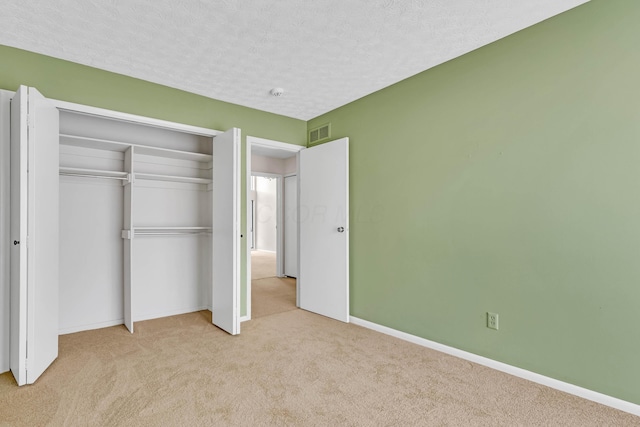 unfurnished bedroom with light colored carpet, a closet, and a textured ceiling