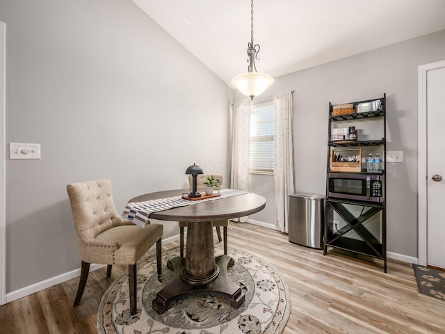 dining area with light hardwood / wood-style floors and vaulted ceiling