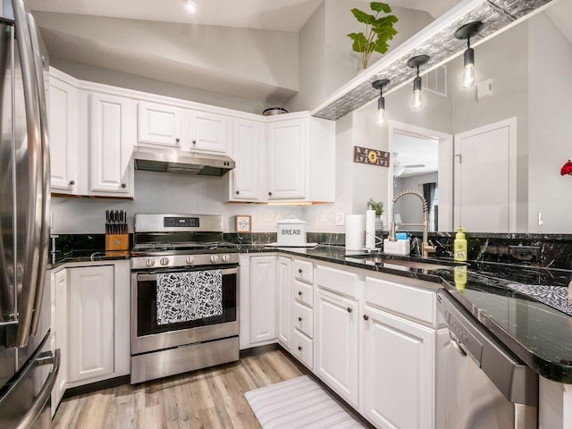 kitchen with sink, appliances with stainless steel finishes, kitchen peninsula, pendant lighting, and white cabinets