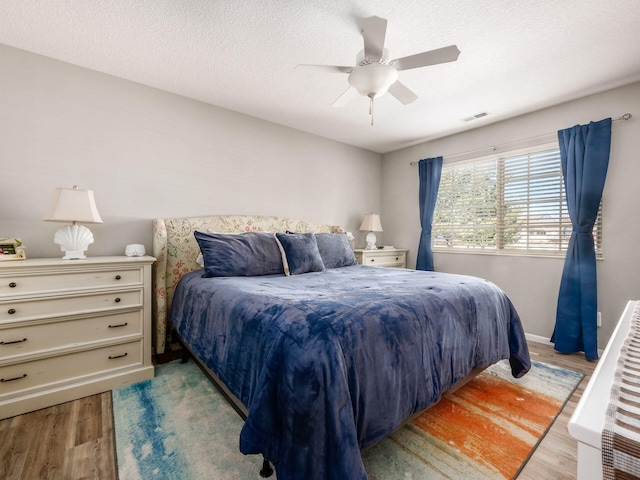 bedroom featuring a textured ceiling, ceiling fan, and light hardwood / wood-style floors