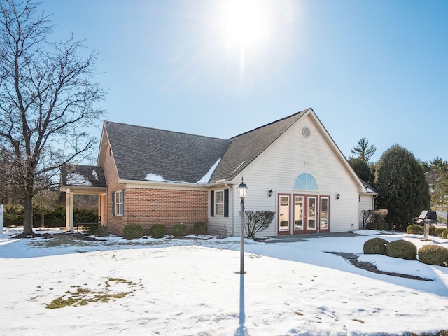 snow covered back of property featuring french doors