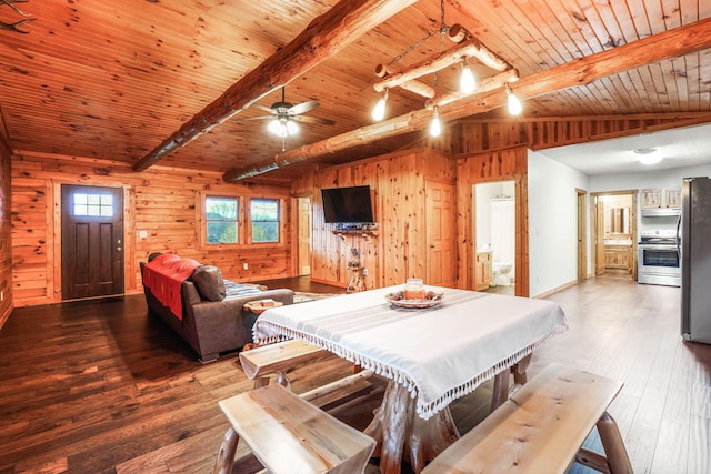 dining space with vaulted ceiling with beams, wood ceiling, wood walls, hardwood / wood-style flooring, and ceiling fan