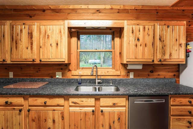 kitchen with stainless steel dishwasher, dark stone counters, and sink