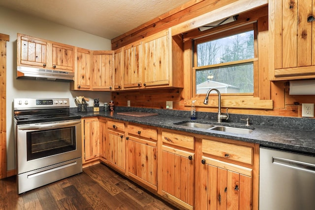 kitchen with sink, dark stone countertops, stainless steel appliances, dark hardwood / wood-style floors, and a textured ceiling