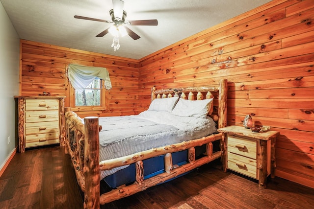 bedroom featuring dark hardwood / wood-style floors, ceiling fan, and wood walls