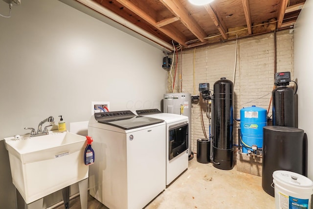 washroom featuring sink, washer and clothes dryer, and brick wall